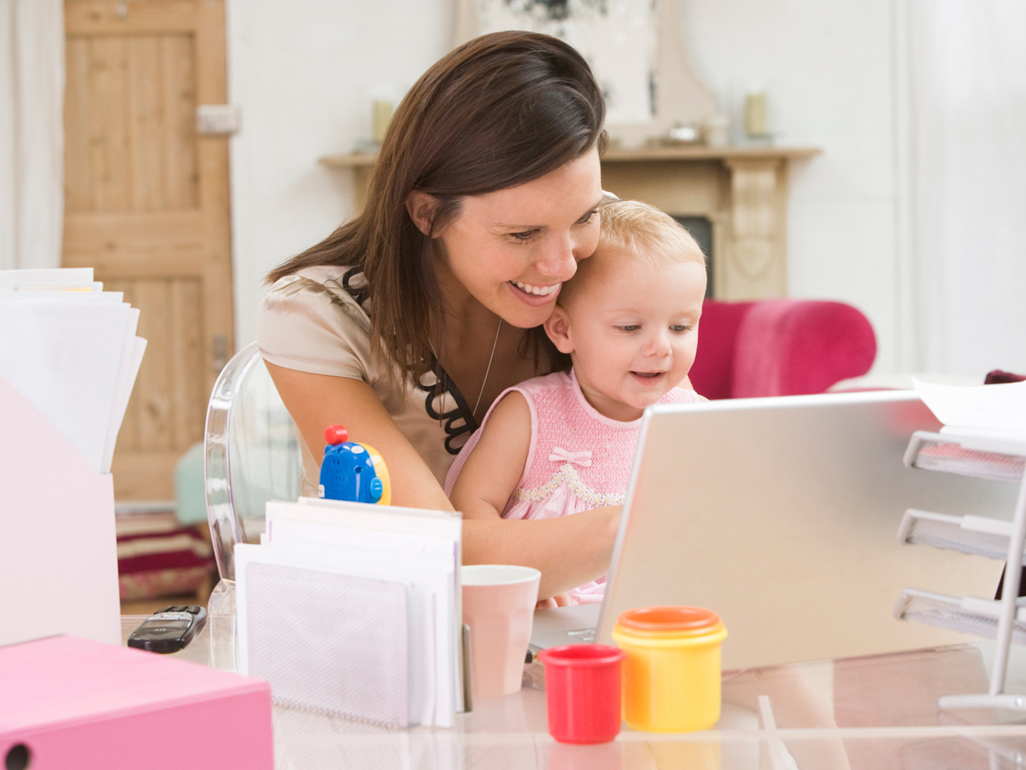 Mother sitting at laptop with baby on her lap