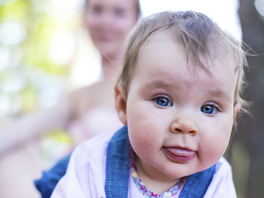 baby boy with blue eyes pokes out tongue
