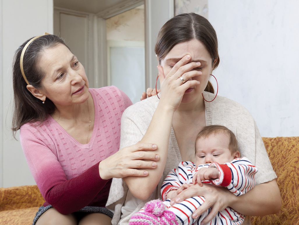 Older woman trying to comfort younger woman who is holding a baby