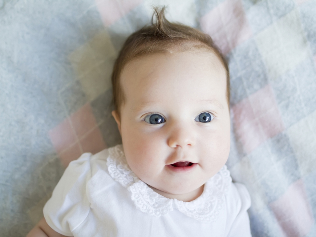 Baby laying on bed looking directly at camera