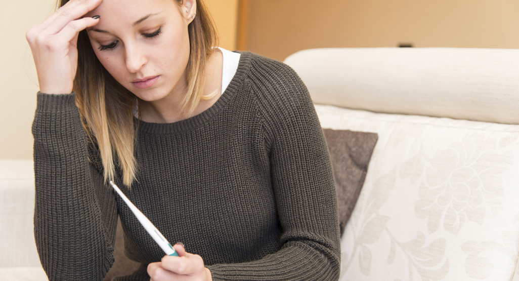 Woman sitting on sofa holding negative pregnancy test