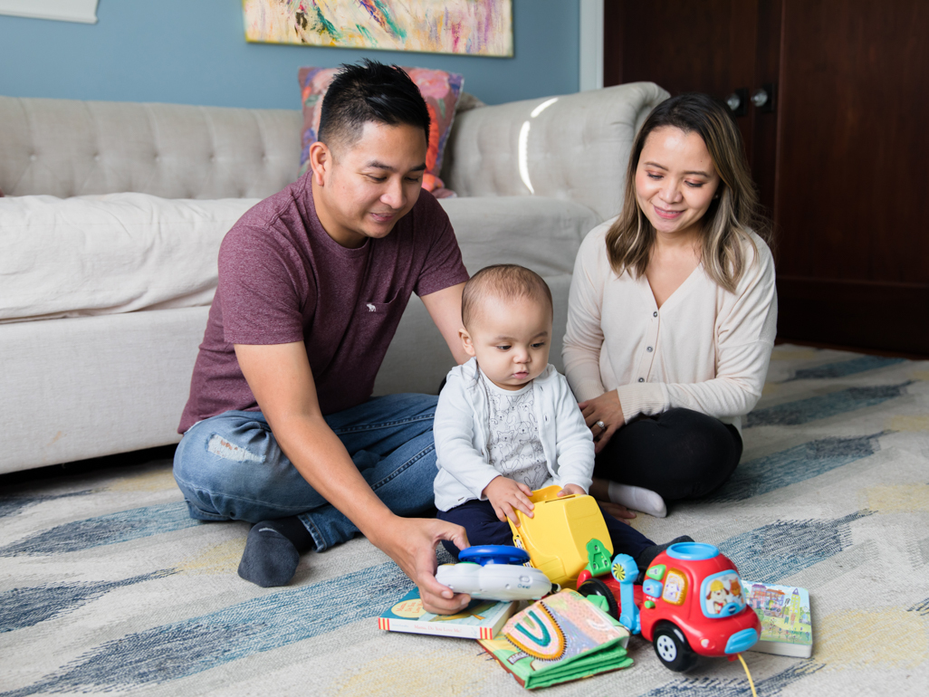 Baby sat on carpet playing with toys with parents