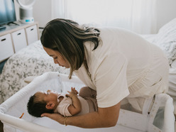Mother placing sleeping baby in crib