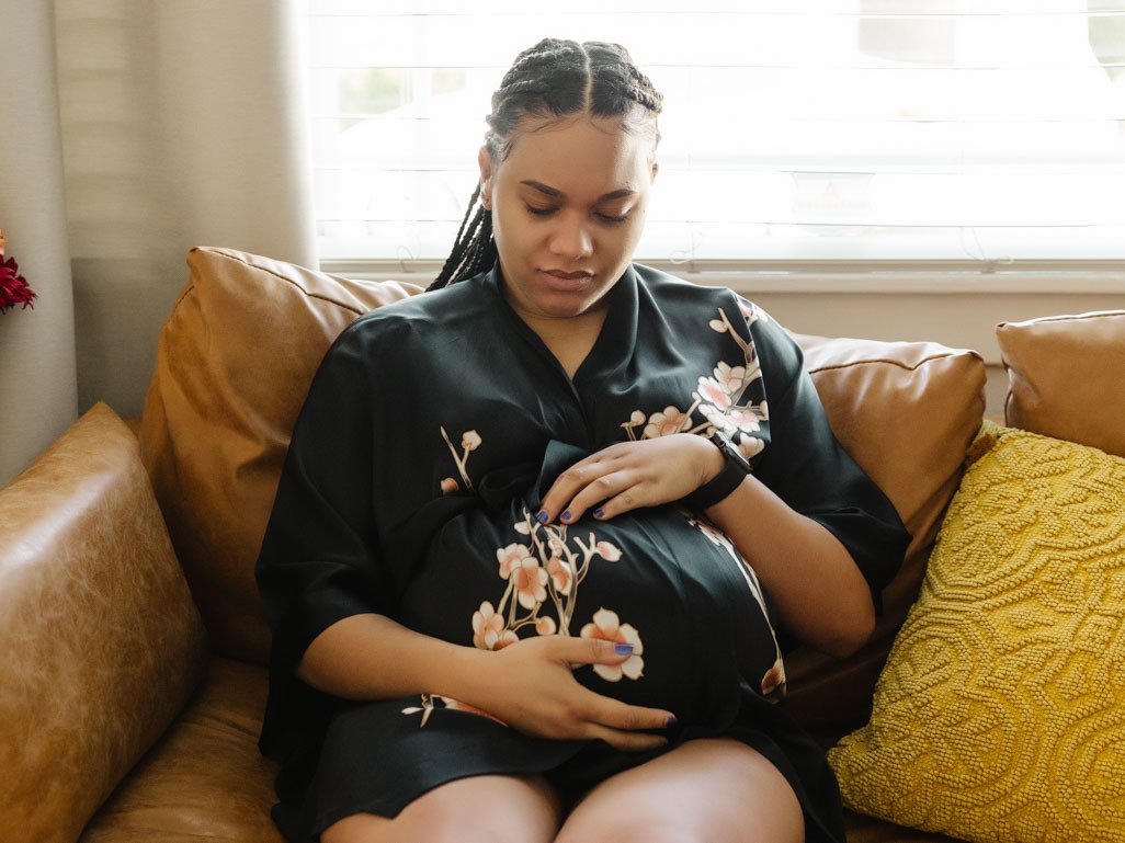 Pregnant woman sitting down holding her bump