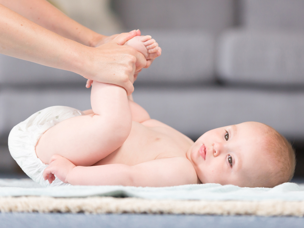 Baby lying on back with hands holding legs up