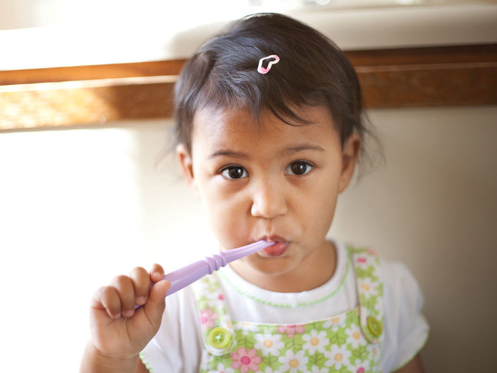 A little girl attempting to brush her teeth