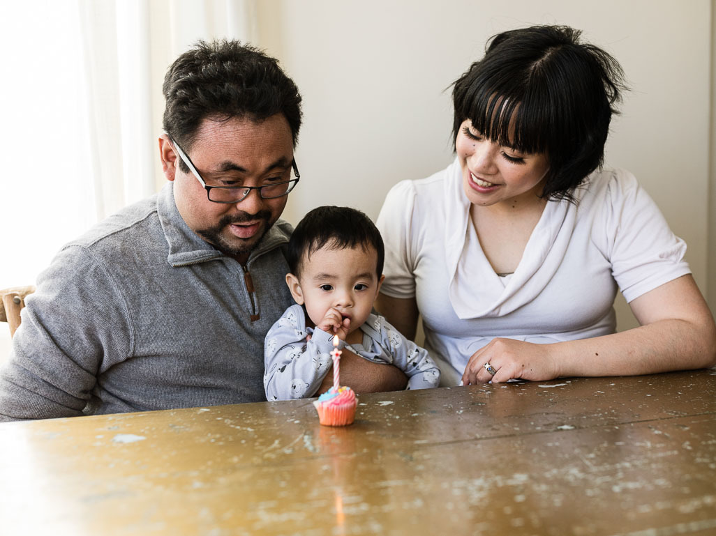 Baby looking at birthday cake on table next to mum and dad