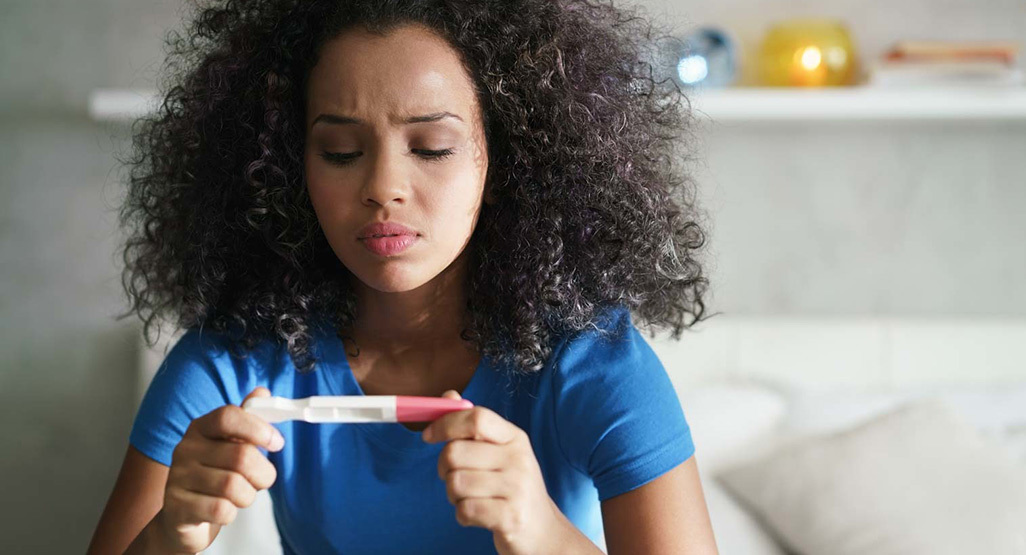 Woman in bathroom looking at pregnancy test result