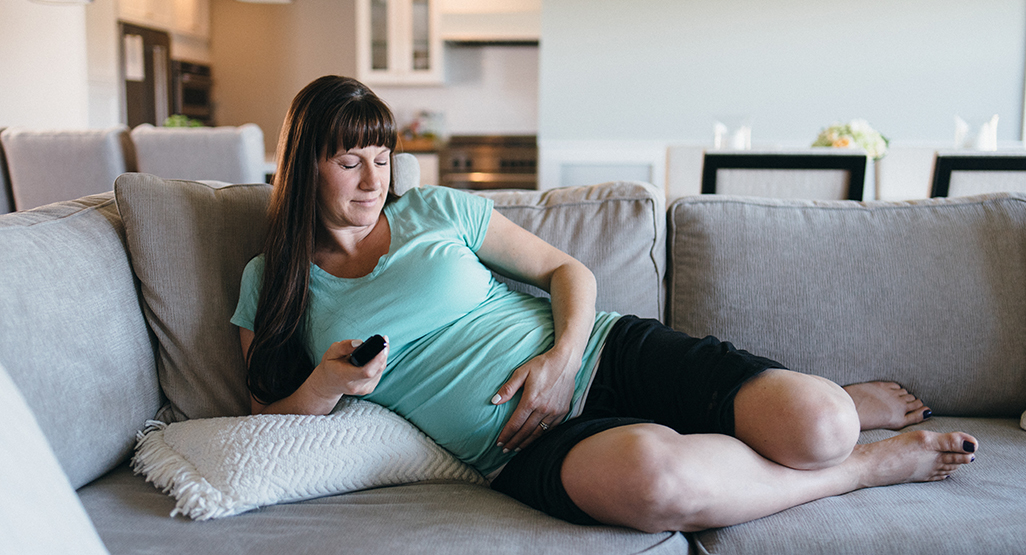 Pregnant woman on the sofa holding her bump