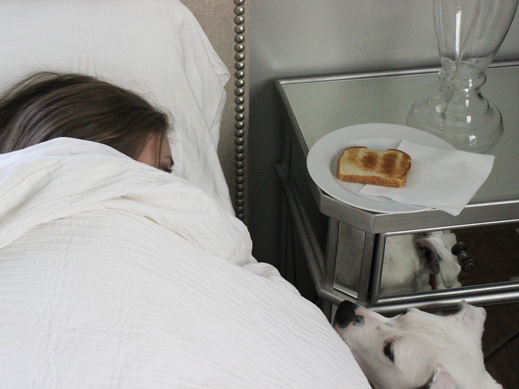 Woman lying in bed with a plain piece of toast on the bedside table