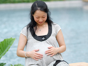 Pregnant woman smiling down at her baby bump