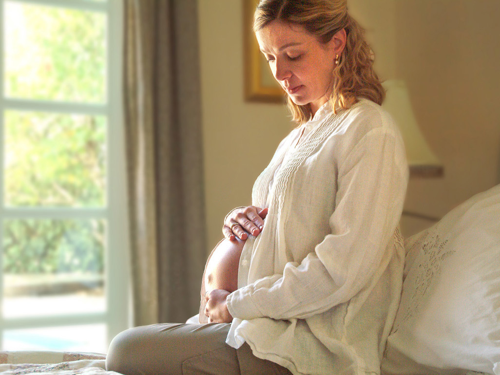 Pregnant woman sitting on bed