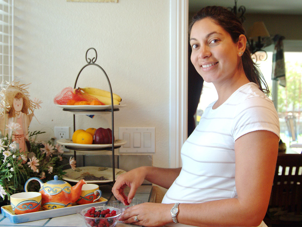 Pregnant woman smiling and preparing breakfast