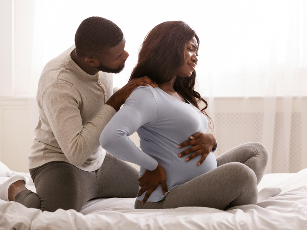 Man comforting his pregnant partner sitting on bed