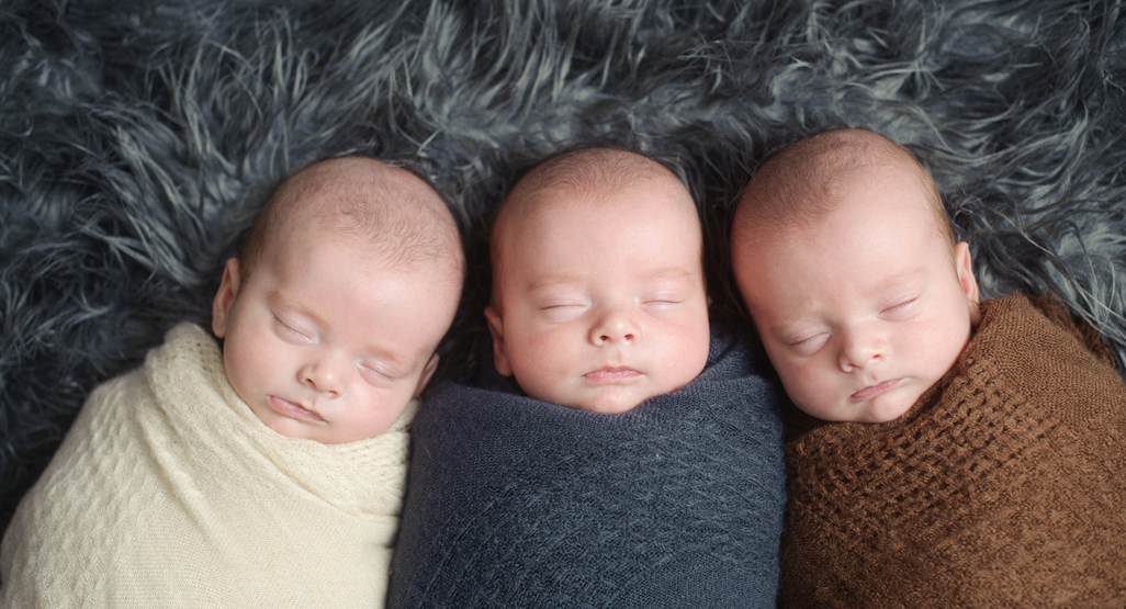 Triplet newborns swaddled in muted colours