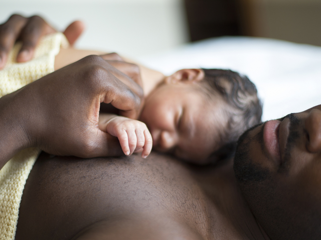 Newborn baby lying on father's chest