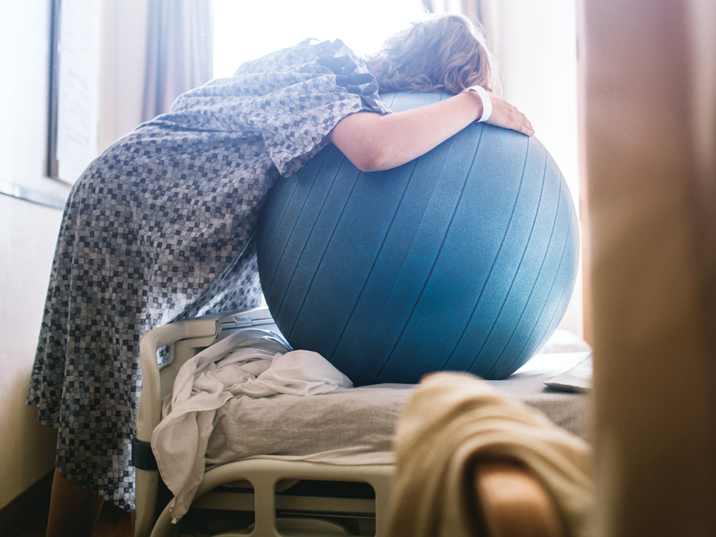 Woman in labour leaning over birth ball