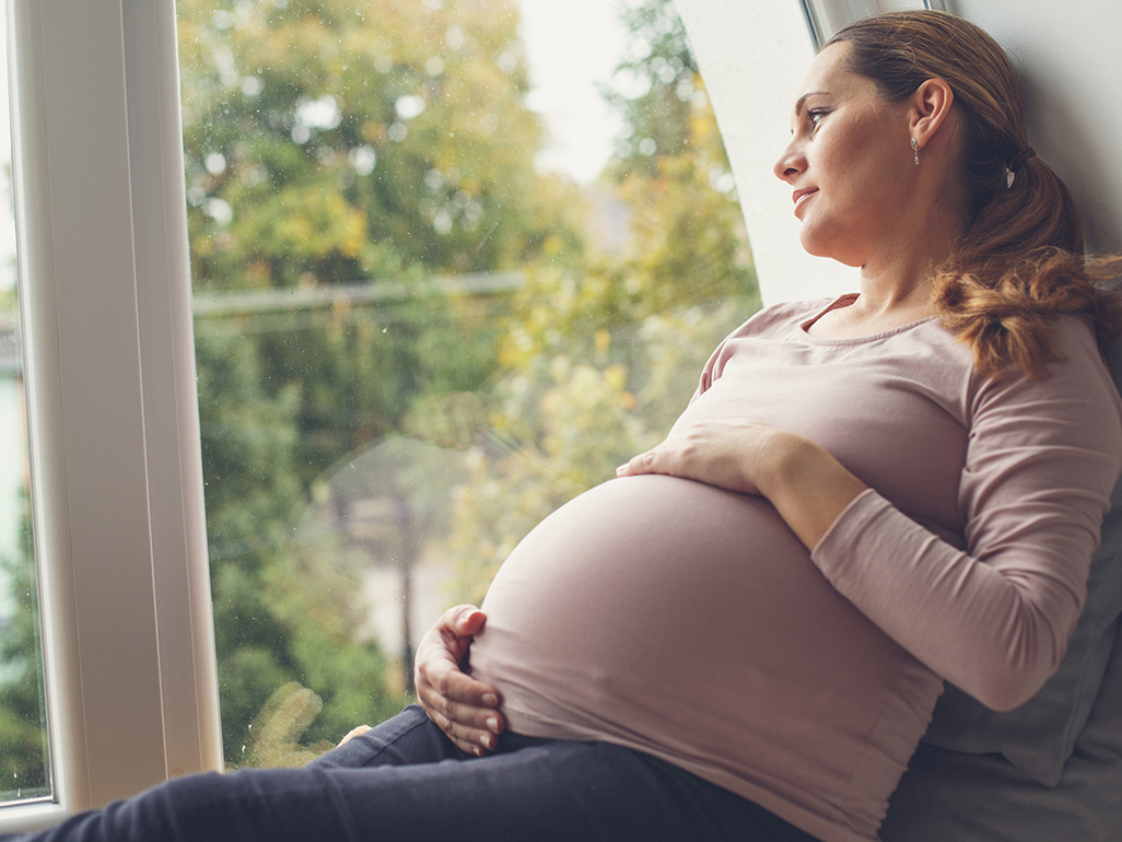 Pregnant woman looking out of the window 