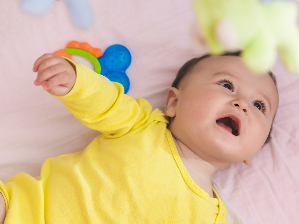 Baby in cot dressed in yellow