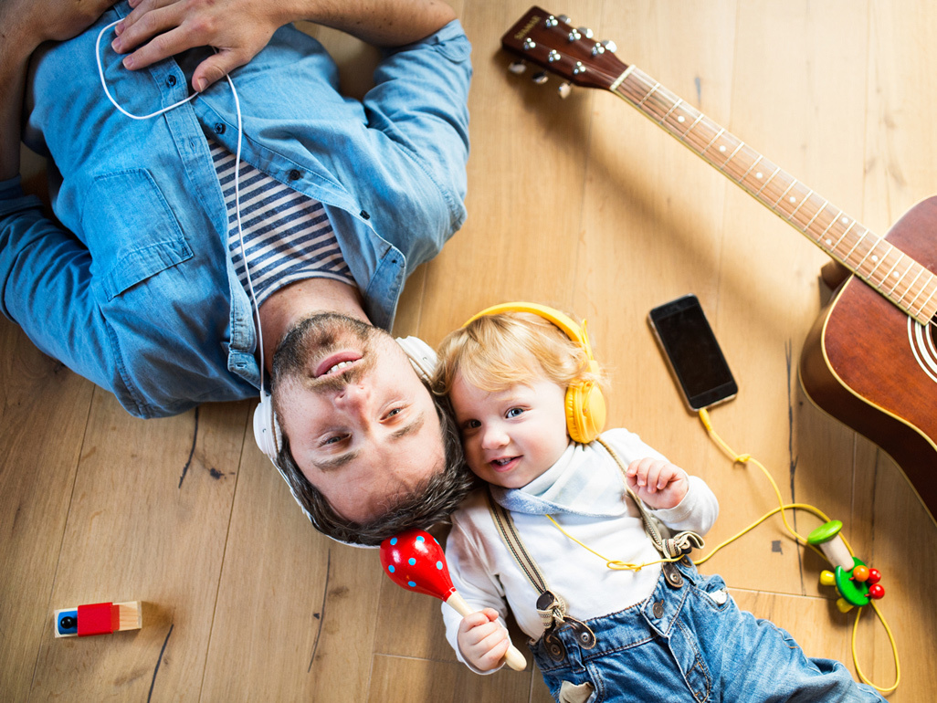 Dad and baby with headphones on and a guitar laying nearby