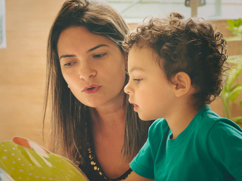 mother and preschooler looking at a book and sounding out the words