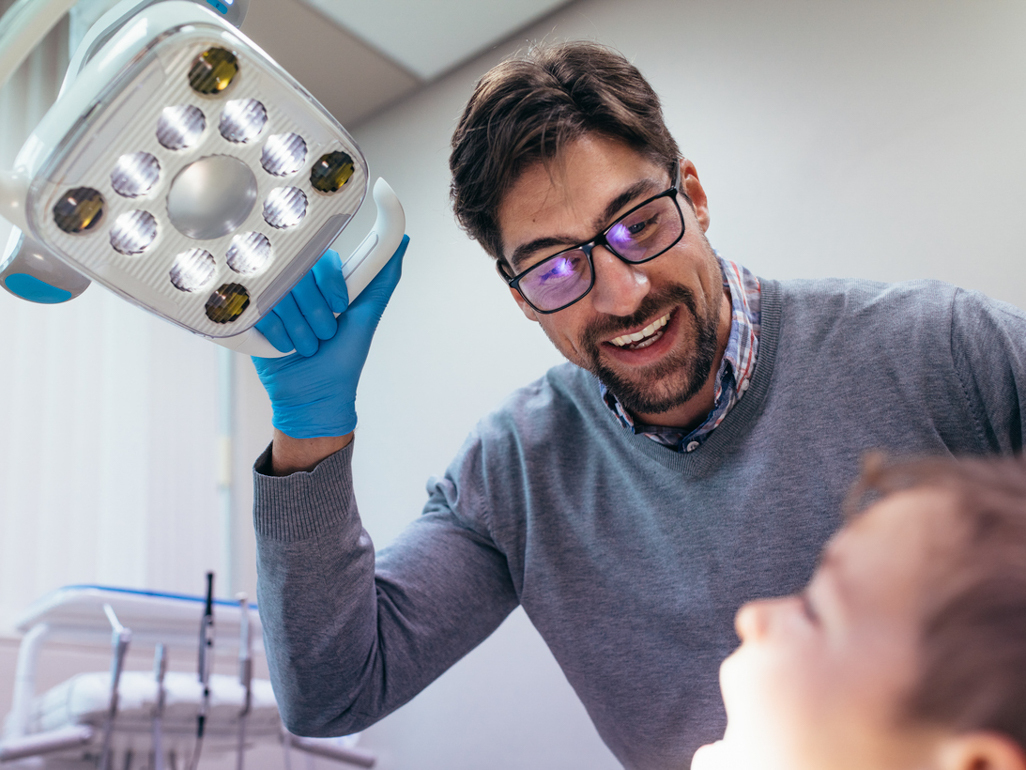 Dentist smiling down at child in a dentist chair 