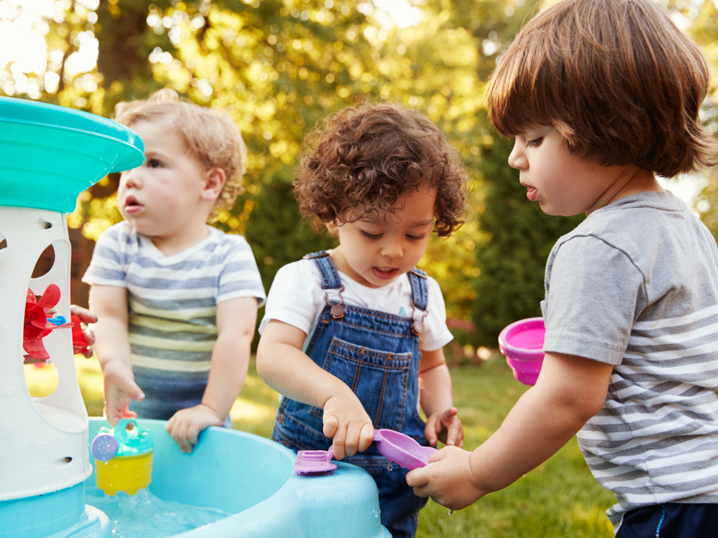 Three preschoolers playing outside together