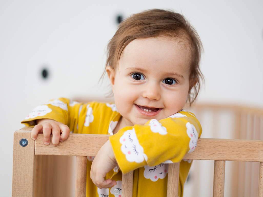 Baby smiling up from her cot