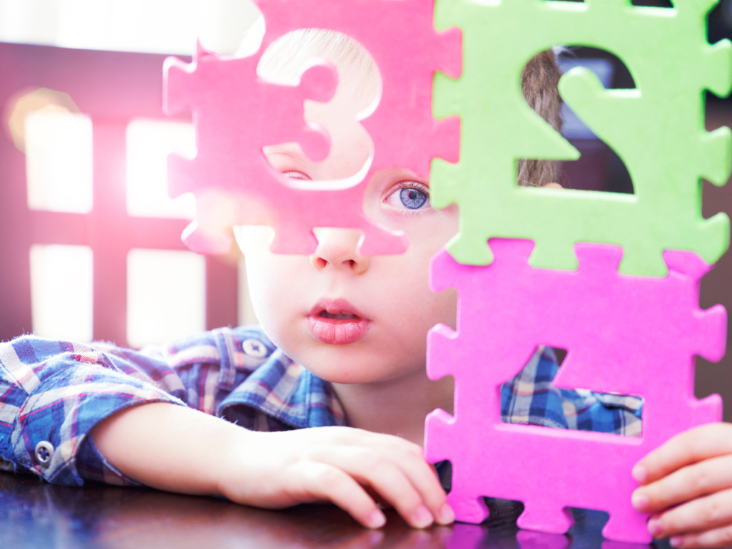 Boy looking through foam tiles with number cut outs