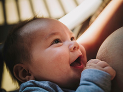 Baby grinning while playing with mother's nipple