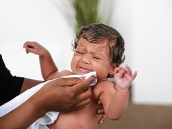 Baby who's just been sick being cleaned with a muslin cloth