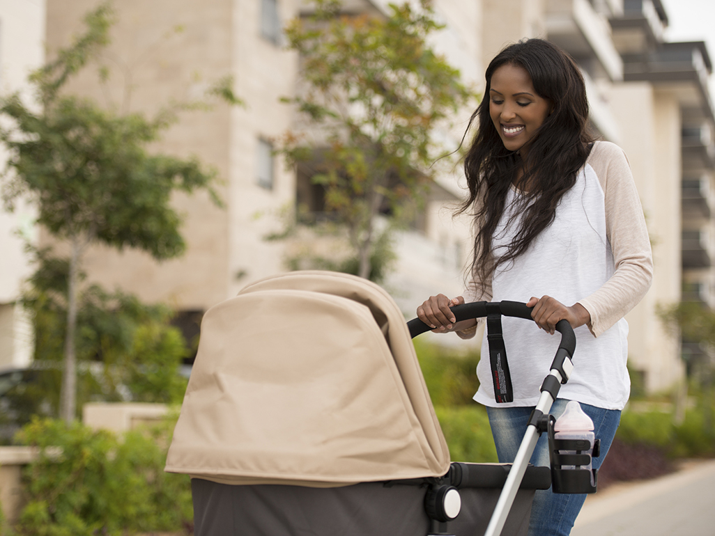 Smiling mum taking baby for a walk in pushchair