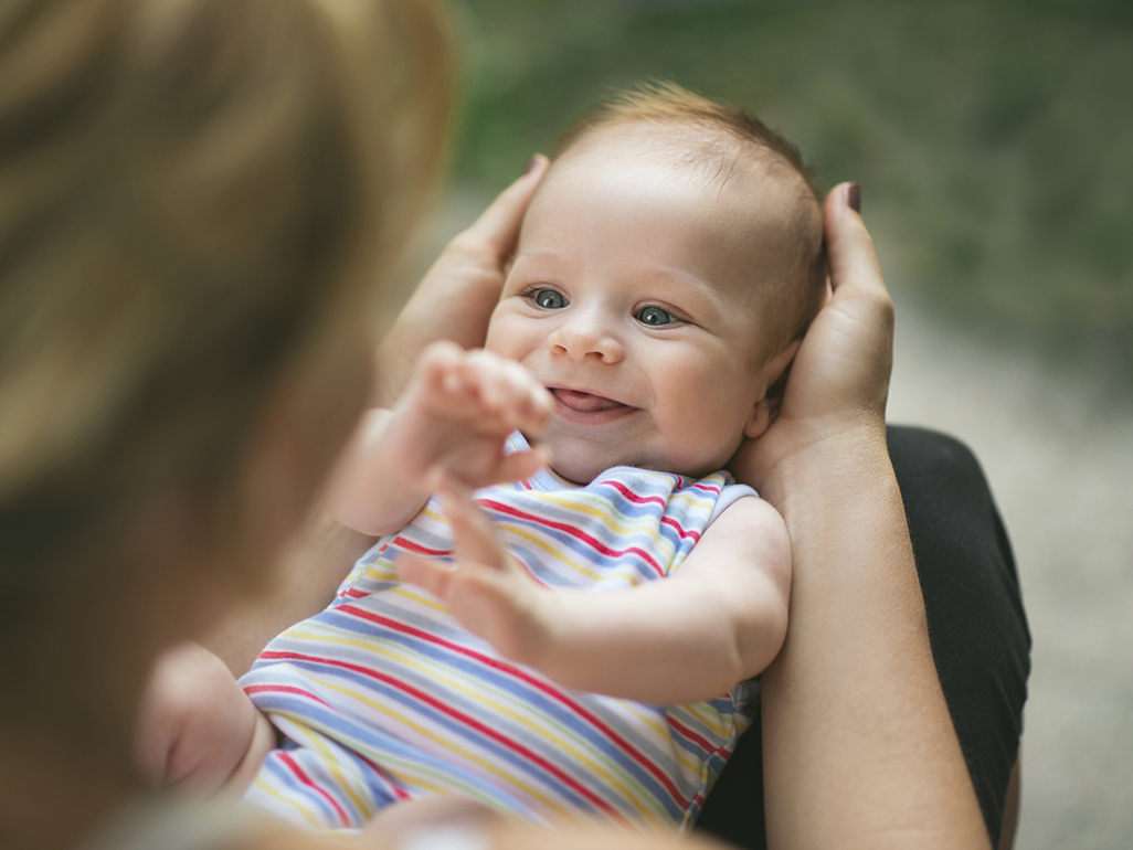 Newborn smiling, lying on mothers lap