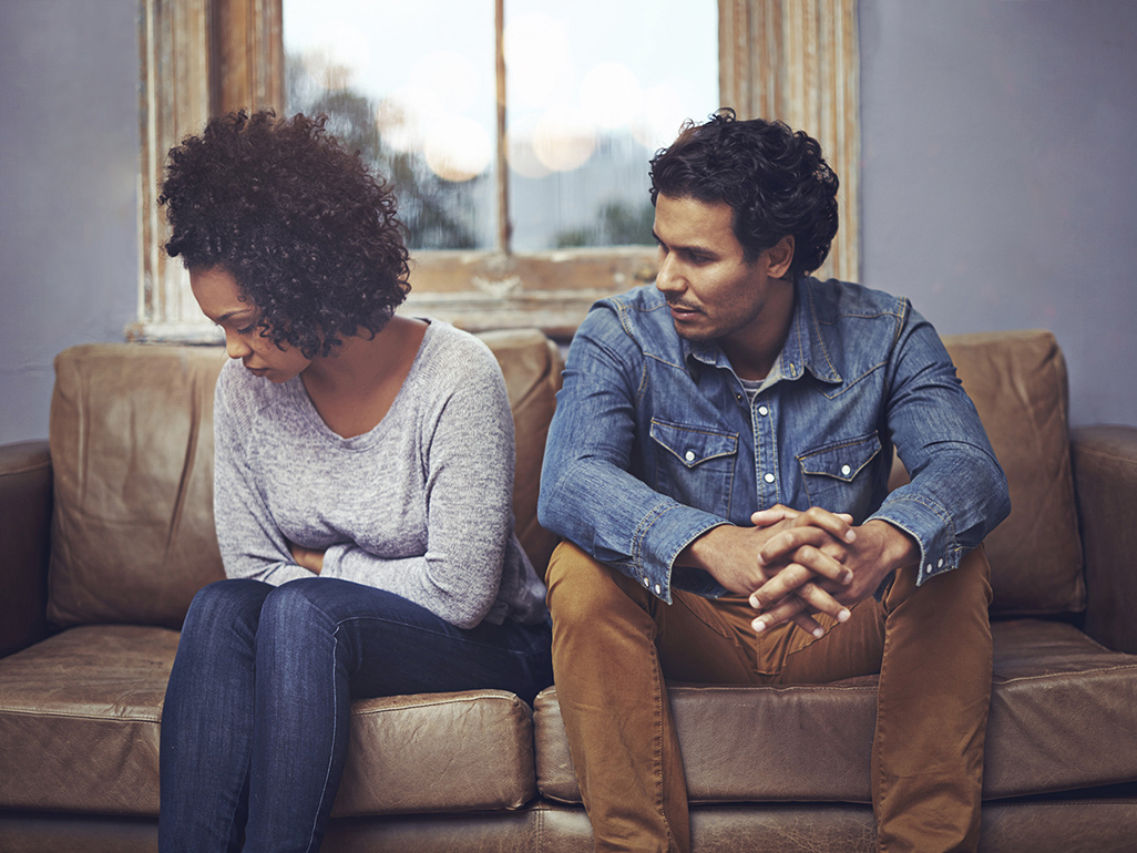 Couple looking emotional sat on sofa