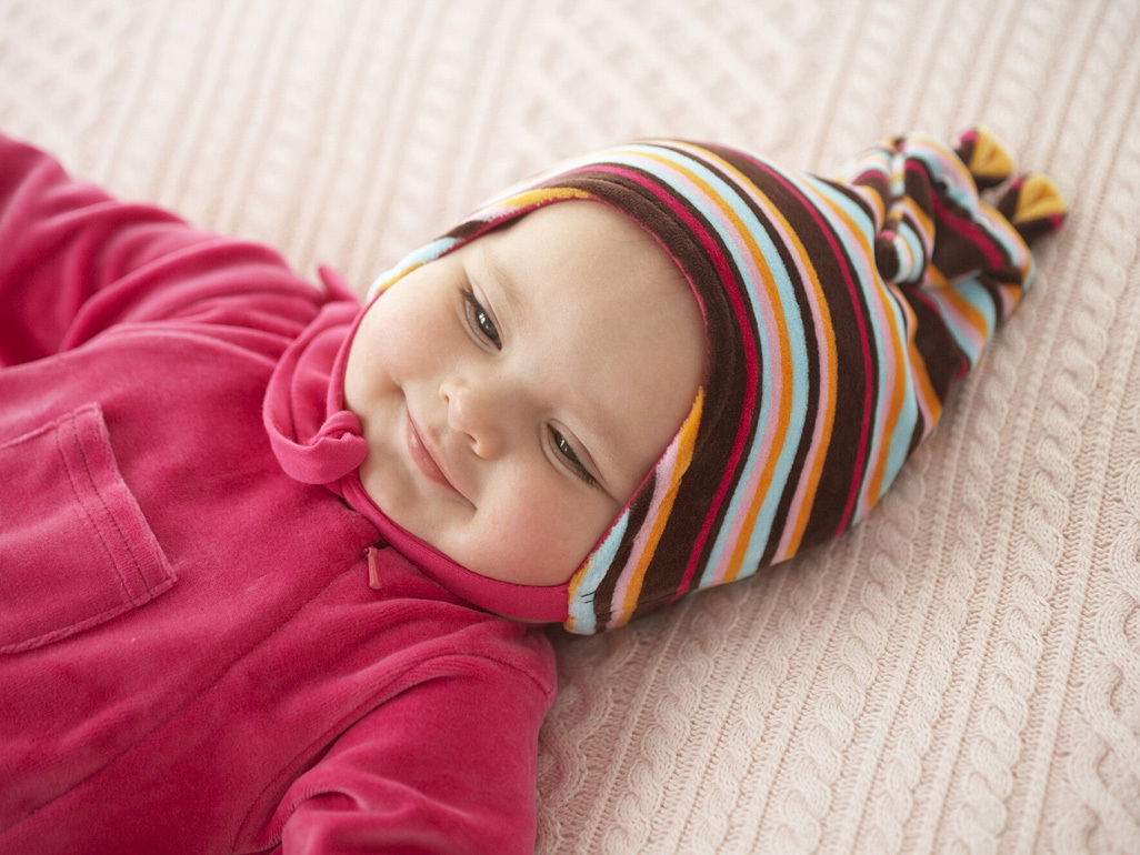 Baby girl lying on back in hat and coat