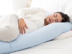 Woman lying in bed asleep with pregnancy pillow