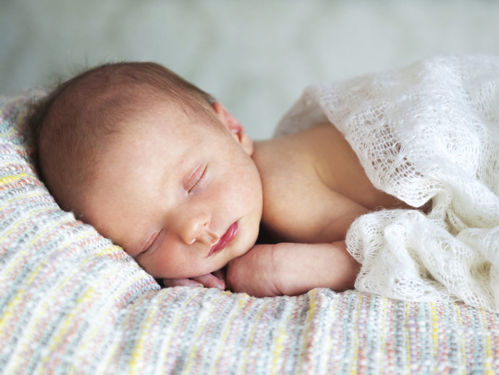 Newborn sleeping peacefully on a blanket.