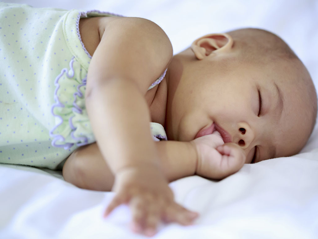 baby girl asleep on her side sucking her thumb