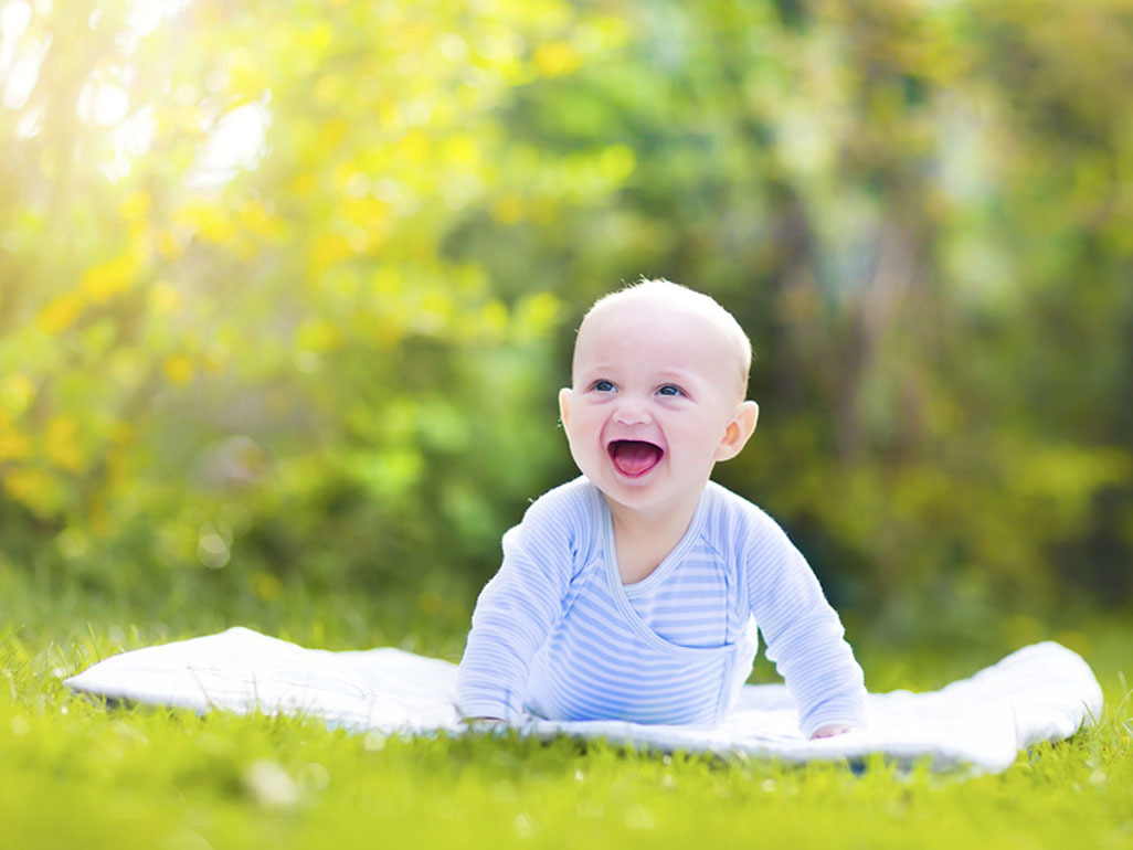 smiling baby outdoors on picnic rug