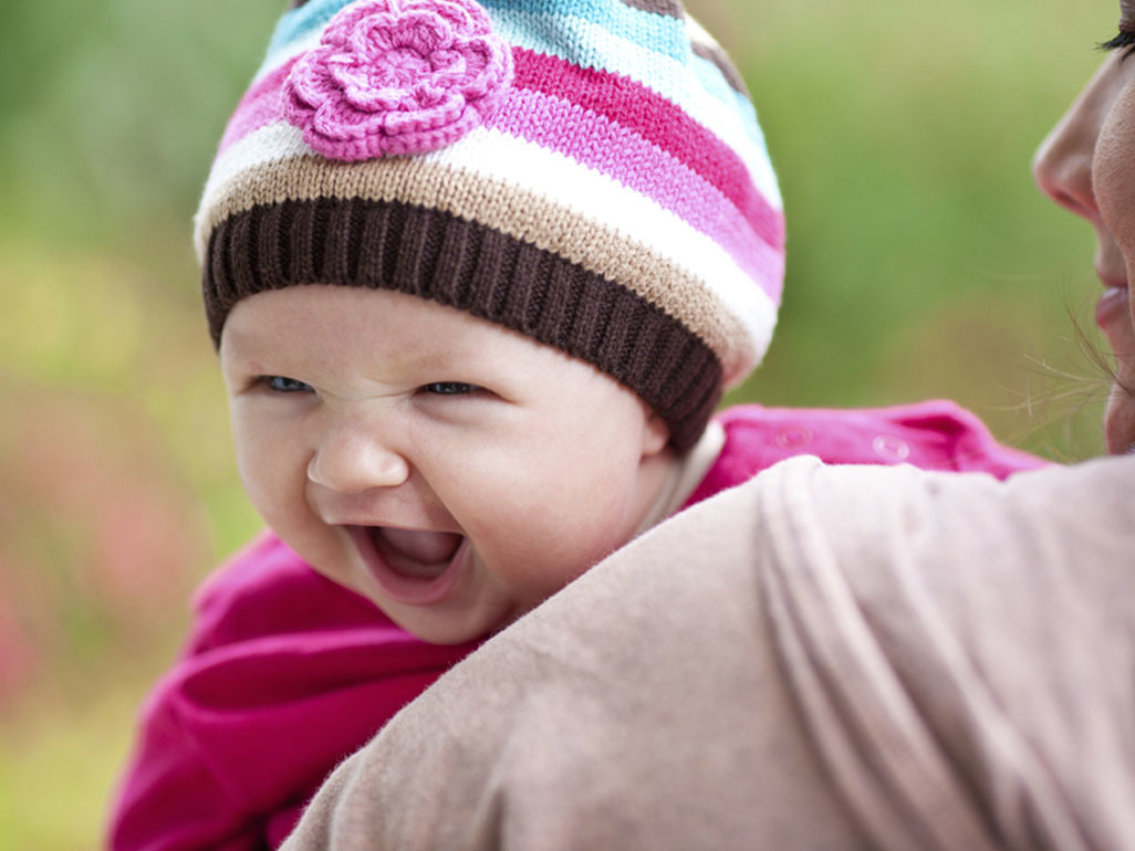 Baby in wool hat laughing 