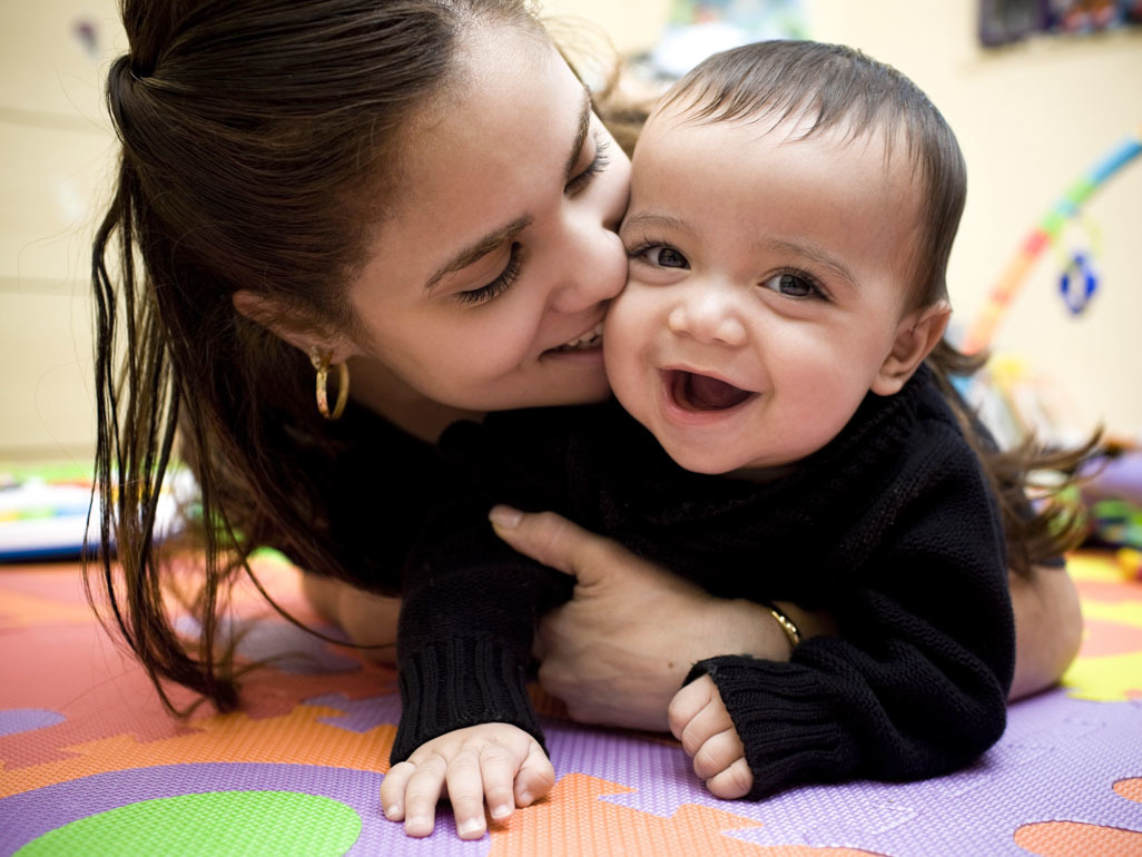 Mother cuddling baby on floor