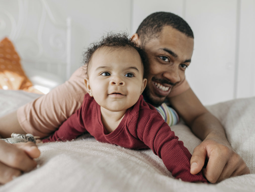 A dad on a bed with his baby