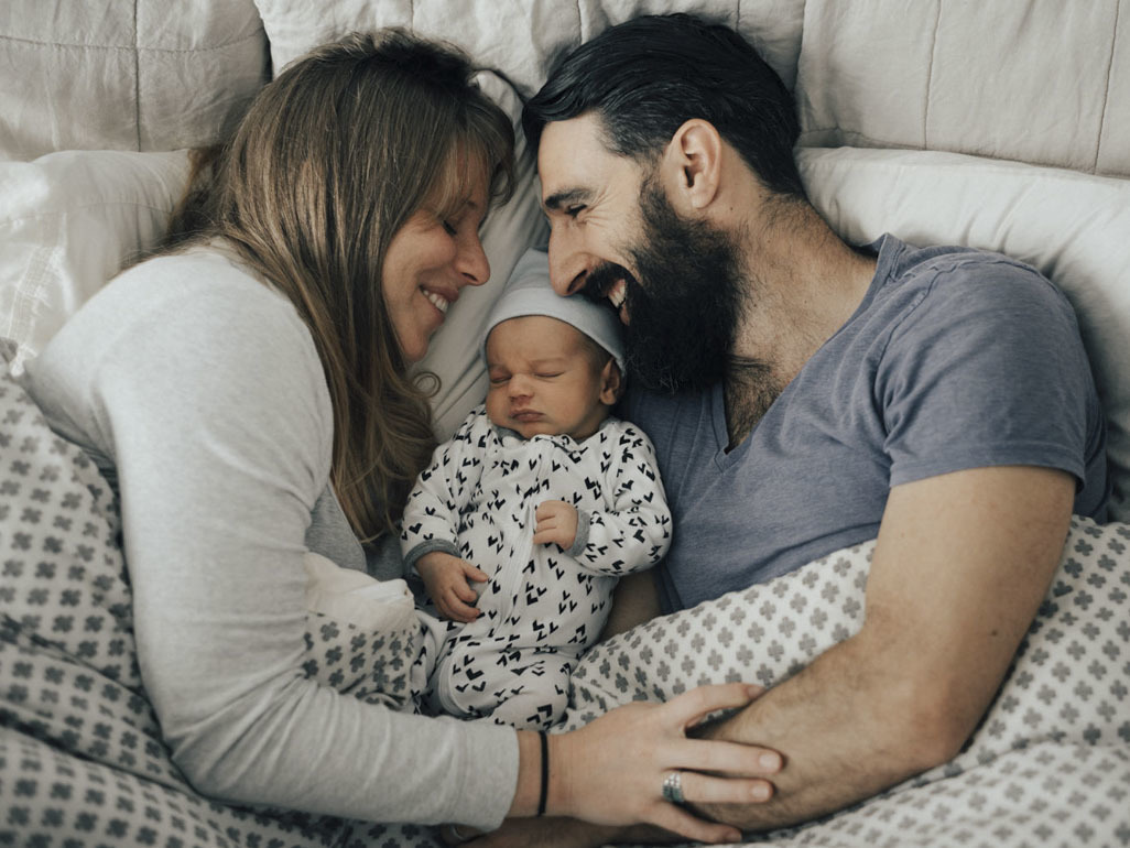Newborn baby lying in between mother and father 